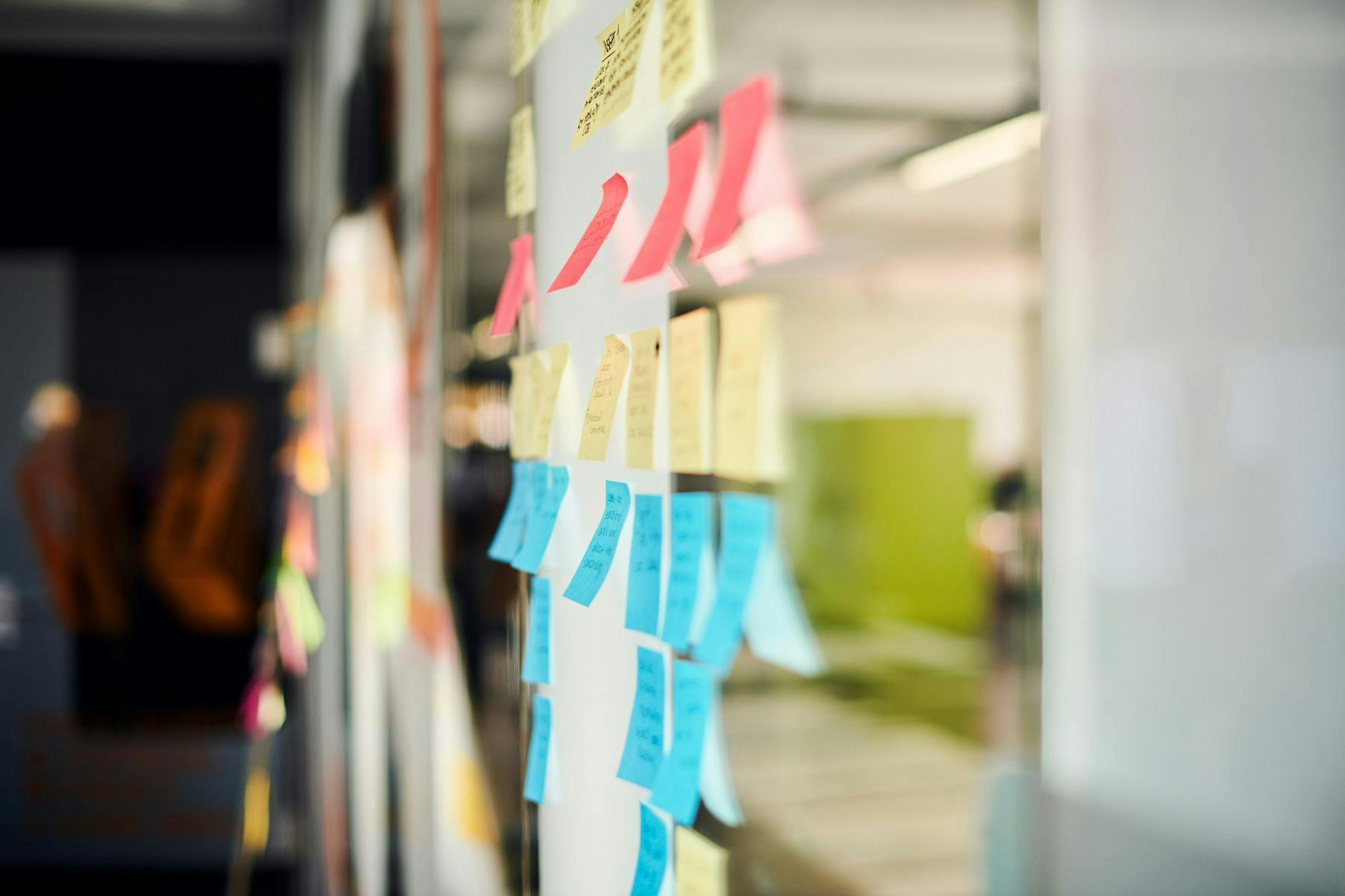 Glass office wall with a group of colourful sticky-notes used for Strategy and UX Research.